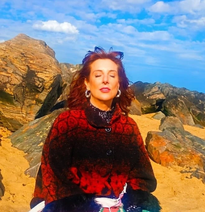 Sara Reiki practitioner in London sitting on a beach with eyes closed in a calm, reflective moment